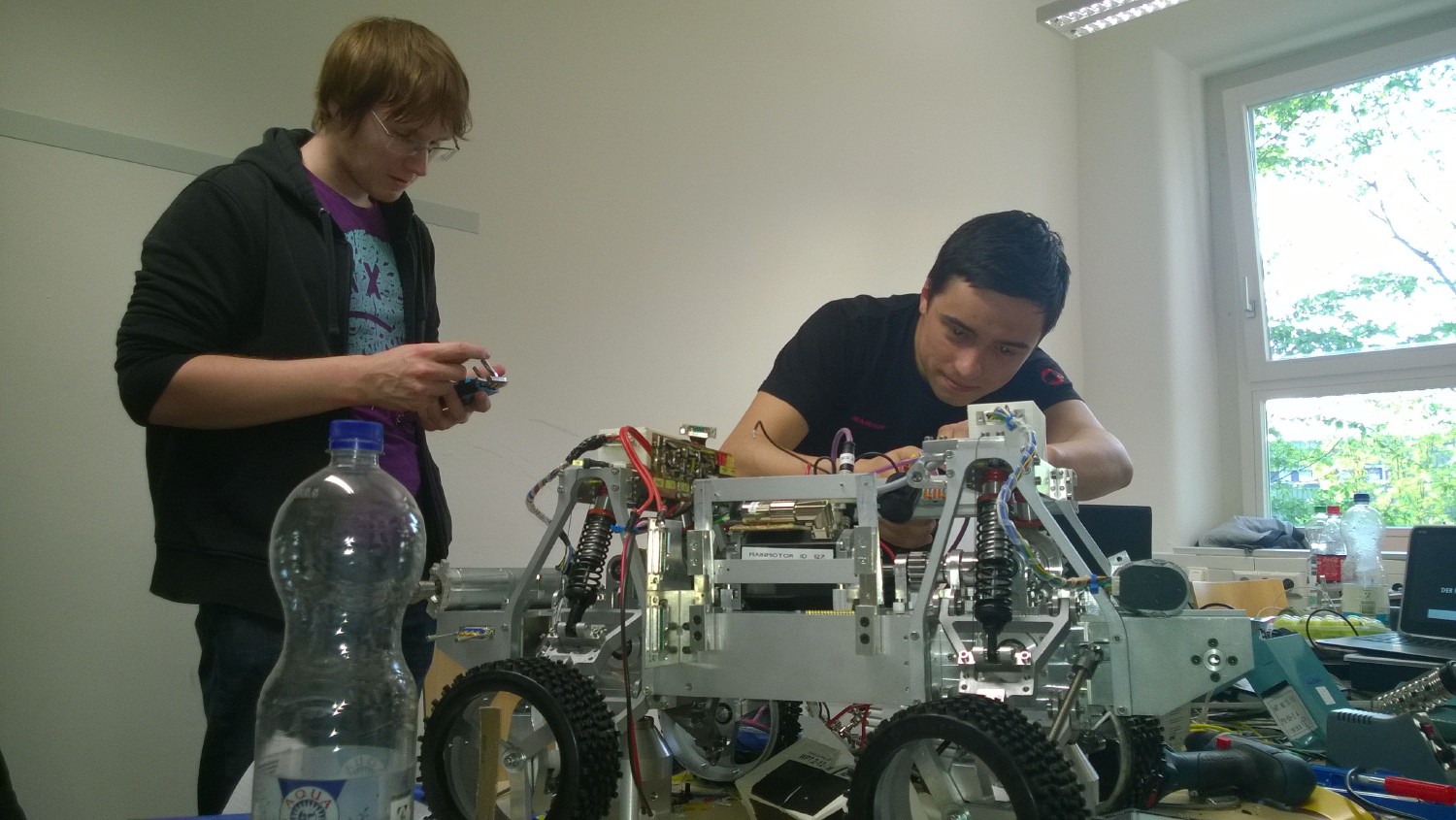 Der Roboter steht auf dem Tisch und zwei Kamaros arbeiten fleißig