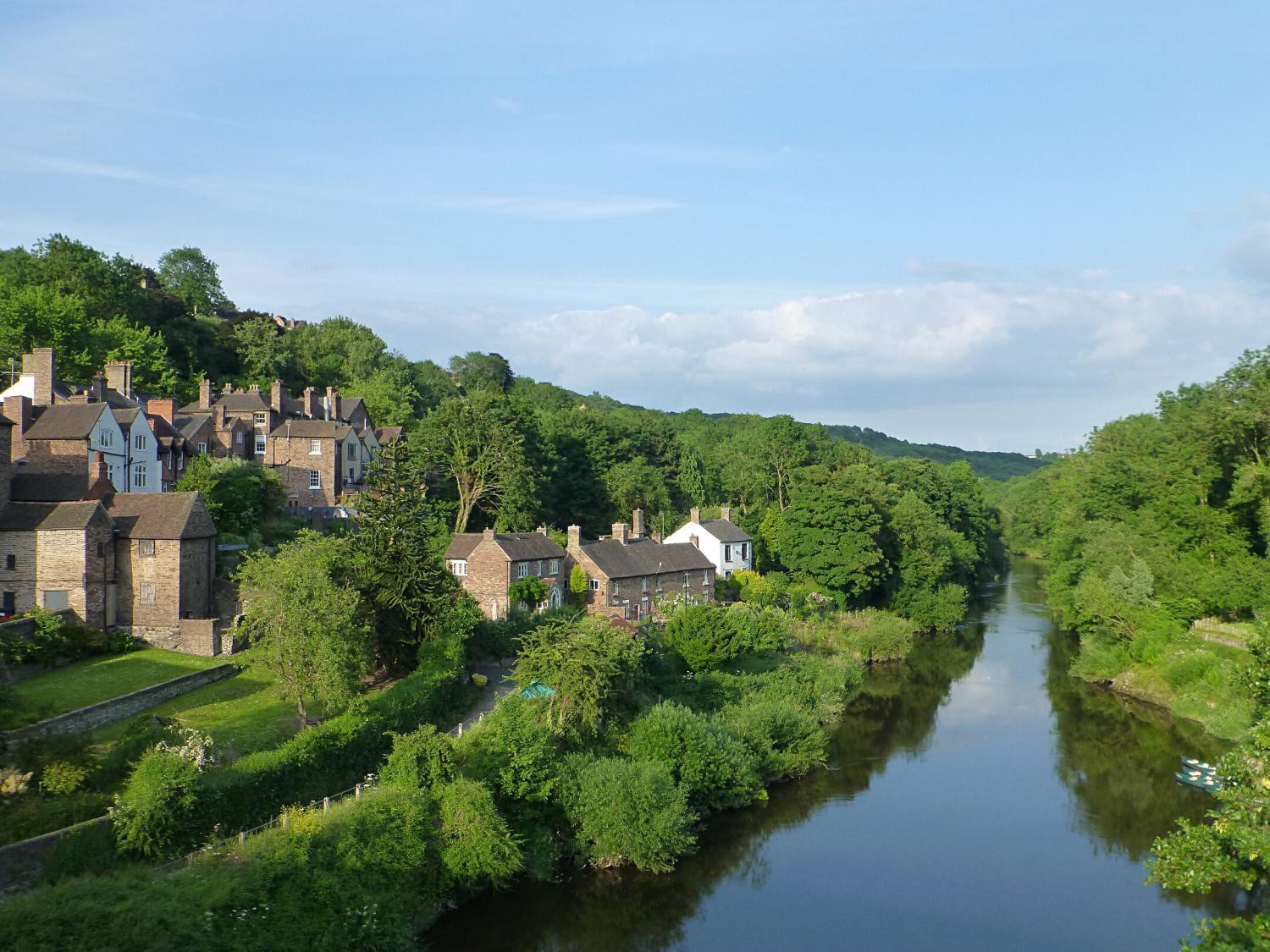 Ein Fluss durchs Grün mit einem Dorf auf der linken Seite