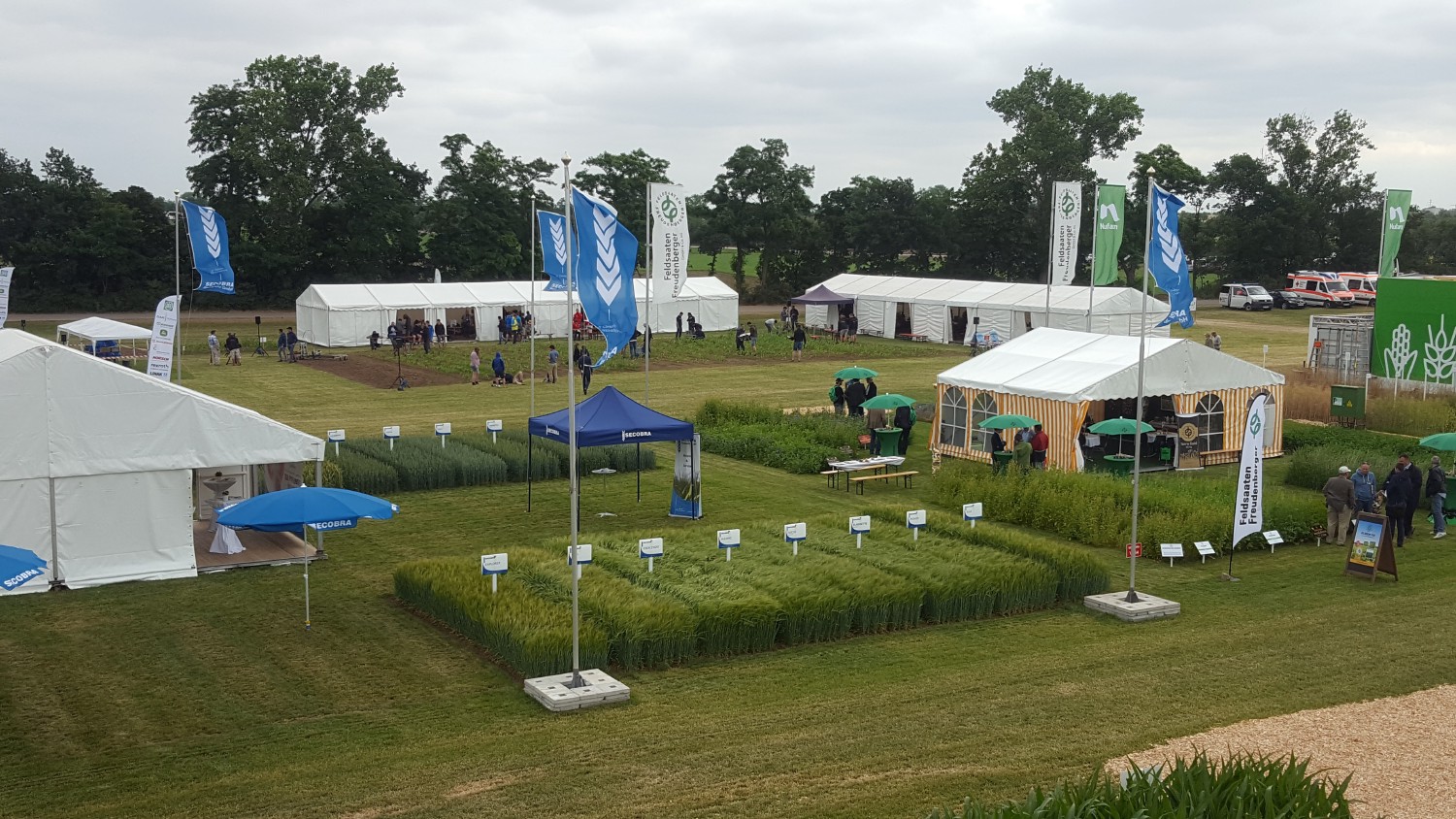 Das Geände der DLG Feldtage. Viele weiße Zelte auf einer Wiese mit kleinen Feldern von Nutzpflanzen dazwischen