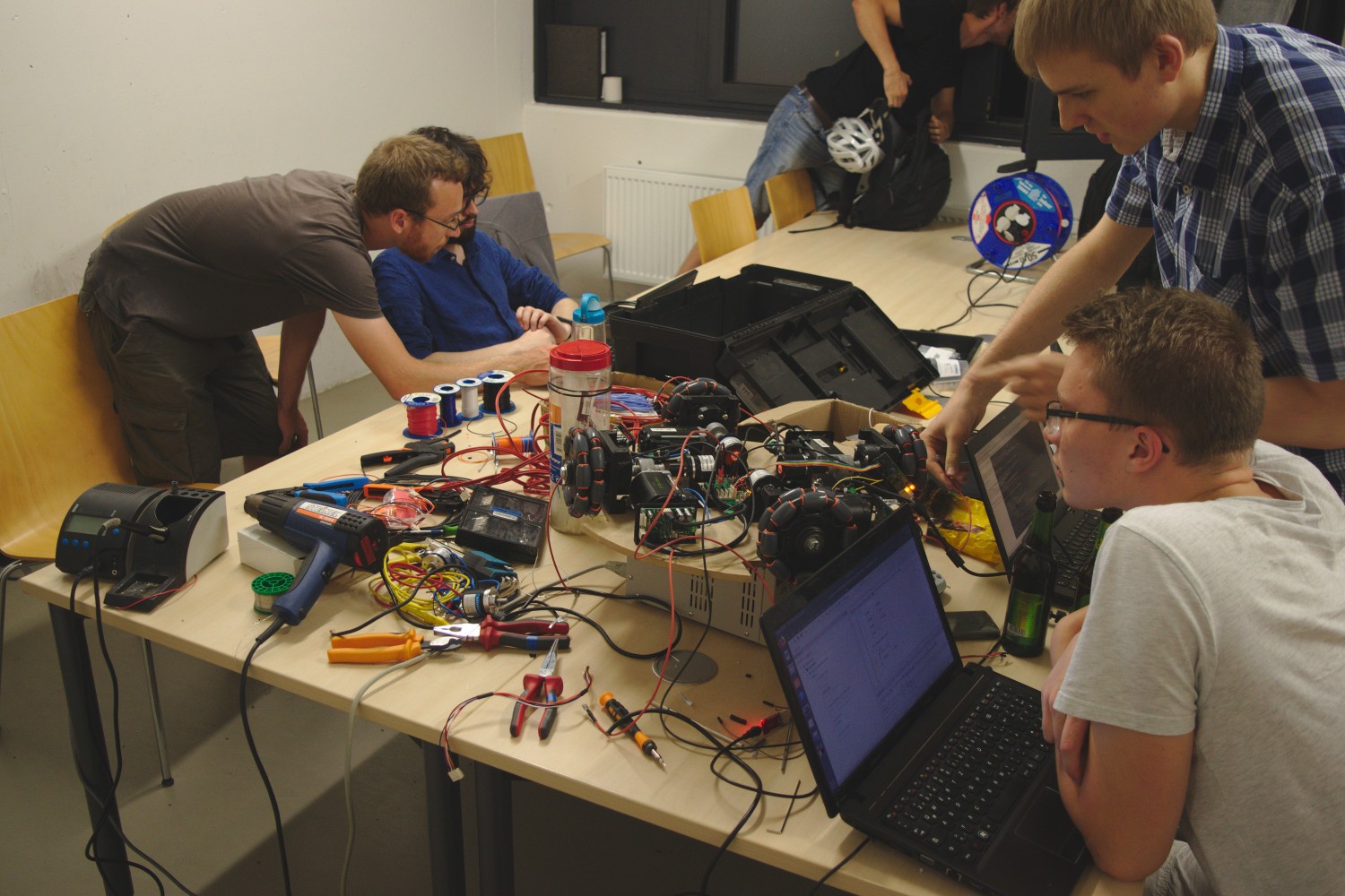 ein Tisch voll mit Kabeln, Werkzeug und Lötkolben mit der Plattform in der Mitte umringt von Kamaros